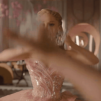 A Woman In A Pink Dress Is Holding A Crown On Her Head GIF