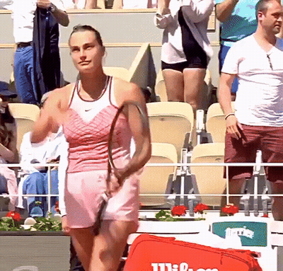 A Woman In A Pink Dress Is Holding A Tennis Racquet GIF