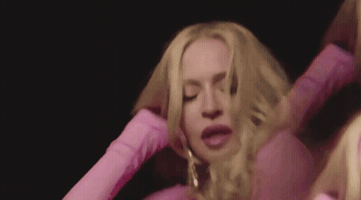 A Woman In A Pink Dress Is Holding Her Hair In Her Hands . GIF