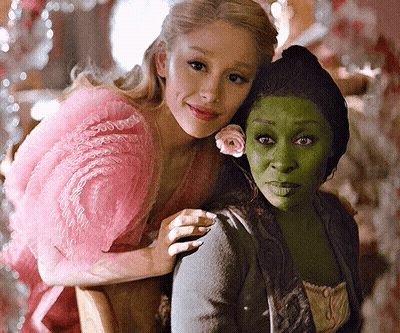 A Woman In A Pink Dress Is Hugging A Woman In A Green Dress GIF