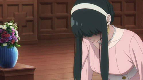 A Woman In A Pink Dress Is Kneeling Down In Front Of A Blue Vase Of Flowers GIF
