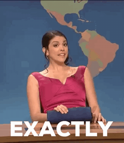 A Woman In A Pink Dress Is Sitting At A Desk With The Words Exactly Written On It . GIF