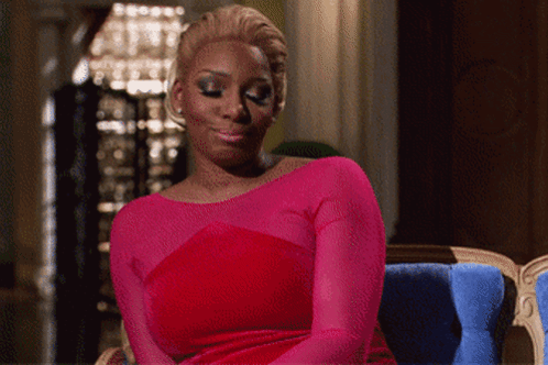 A Woman In A Pink Dress Is Sitting In A Blue Chair GIF