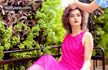 A Woman In A Pink Dress Is Sitting On A Bench While A Man Holds Her Hair . GIF