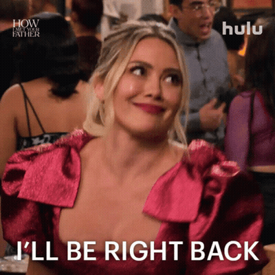 A Woman In A Pink Dress Is Smiling And Says I 'Ll Be Right Back GIF