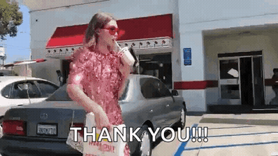 A Woman In A Pink Dress Is Standing In Front Of A Car Holding A Cup Of Coffee And A Bag Of Food . GIF