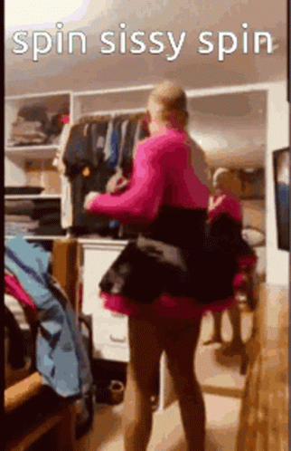 A Woman In A Pink Dress Is Standing In Front Of A Closet . GIF