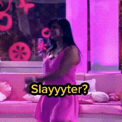 A Woman In A Pink Dress Is Standing In Front Of A Couch With The Words Slayyyter On It GIF