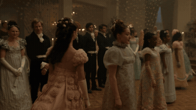 A Woman In A Pink Dress Is Standing In Front Of A Man In A Black Suit GIF