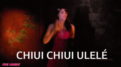 A Woman In A Pink Dress Is Standing In Front Of A Sign That Says Chiui Chiui Ulele GIF