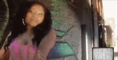 A Woman In A Pink Dress Is Standing In Front Of A Wall With Graffiti On It . GIF