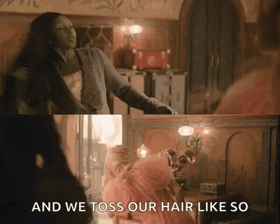 A Woman In A Pink Dress Is Standing Next To A Woman In A Green Dress In A Room . GIF