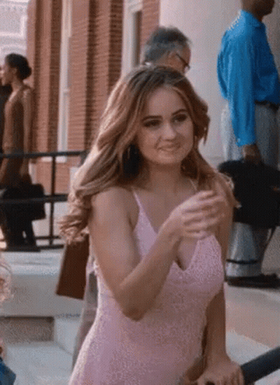A Woman In A Pink Dress Is Standing On The Steps Of A Building . GIF