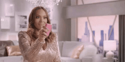 A Woman In A Pink Dress Is Taking A Selfie With Her Cell Phone . GIF