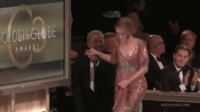 A Woman In A Pink Dress Is Walking On A Stage At The Golden Globe Awards GIF