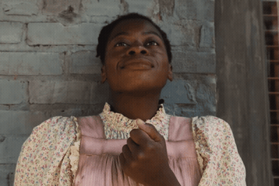 A Woman In A Pink Dress Looks Up At The Sky GIF
