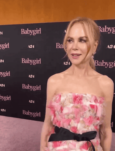 A Woman In A Pink Dress Stands In Front Of A Wall With Babygirl Written On It GIF
