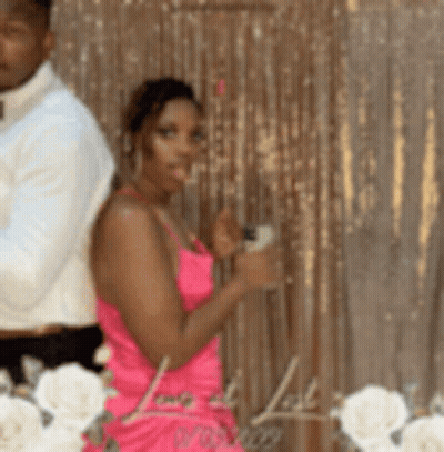 A Woman In A Pink Dress Stands Next To A Man In A White Shirt . GIF