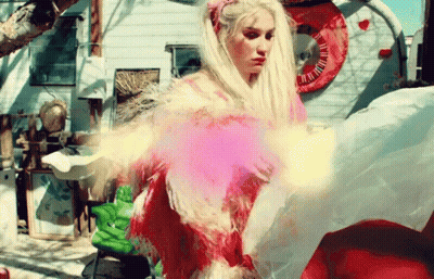 A Woman In A Pink Dress With Feathers Is Standing In Front Of A Trailer GIF