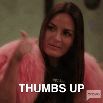 A Woman In A Pink Fur Coat Is Giving A Thumbs Up Sign GIF