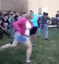 A Woman In A Pink Jacket And Blue Skirt Is Running In The Grass GIF