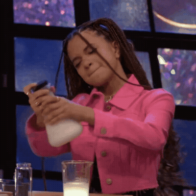 A Woman In A Pink Jacket Is Pouring Milk Into A Cup GIF