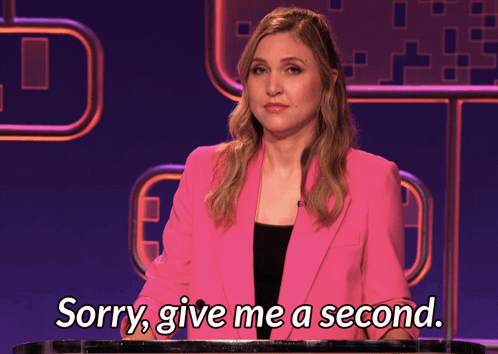 A Woman In A Pink Jacket Is Saying " Sorry Give Me A Second " GIF