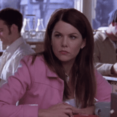 A Woman In A Pink Jacket Is Sitting At A Table With Other People GIF