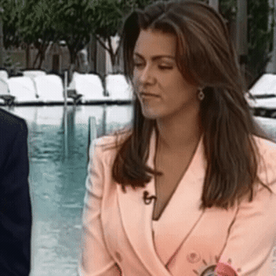 A Woman In A Pink Jacket Is Sitting Next To A Pool . GIF