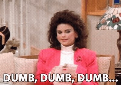 A Woman In A Pink Jacket Is Sitting On A Couch And Says Dumb Dumb Dumb .. GIF