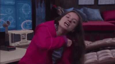 A Woman In A Pink Jacket Is Standing In Front Of A Computer Screen . GIF