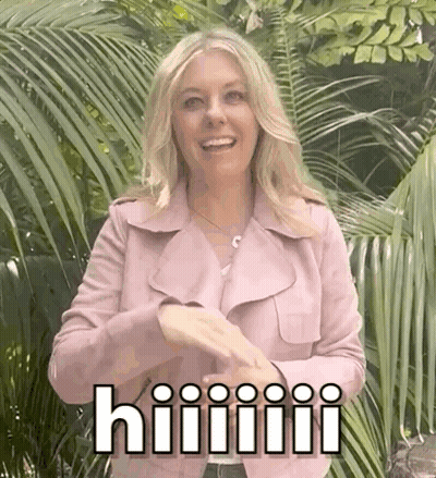 A Woman In A Pink Jacket Is Standing In Front Of Palm Trees And Making A Funny Face . GIF