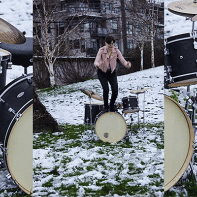 A Woman In A Pink Jacket Is Standing On A Drum Set In The Snow GIF
