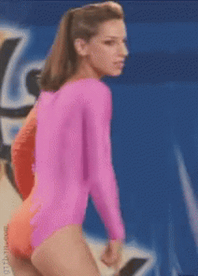 A Woman In A Pink Leotard Stands In Front Of A Blue Background GIF