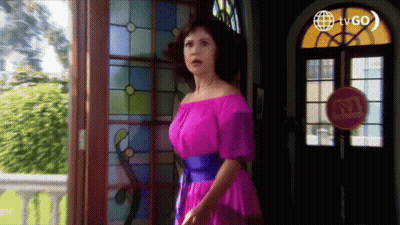A Woman In A Pink Off The Shoulder Dress Stands In Front Of A Stained Glass Window . GIF