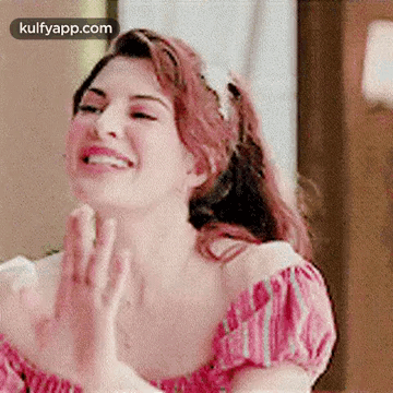 A Woman In A Pink Off The Shoulder Top Is Clapping Her Hands . GIF