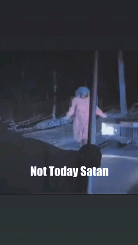 A Woman In A Pink Robe Is Holding A Gun In Front Of A Car With The Words " Not Today Satan " Below Her GIF