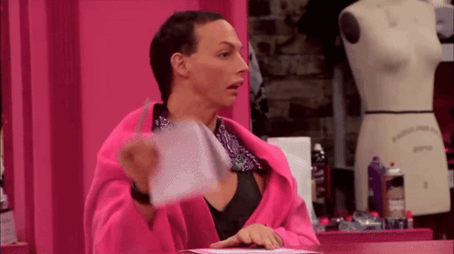 A Woman In A Pink Robe Is Holding A Piece Of Paper In Front Of A Mannequin GIF