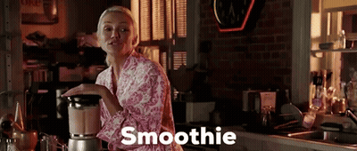 A Woman In A Pink Robe Is Making A Smoothie GIF