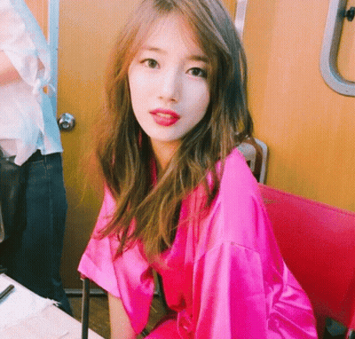 A Woman In A Pink Robe Sits In A Chair GIF
