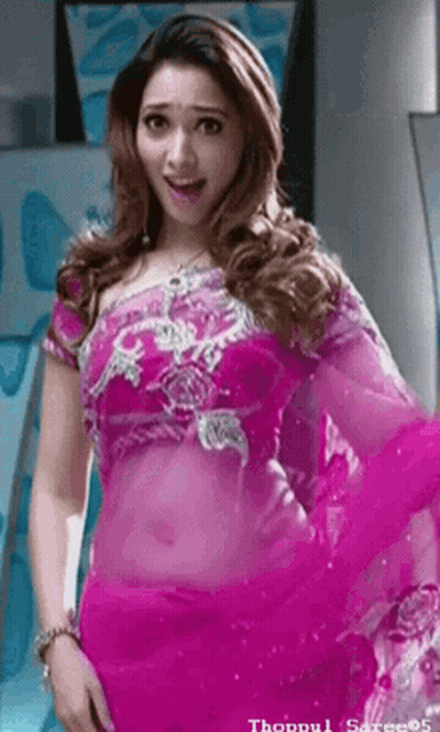 A Woman In A Pink Saree Is Standing In Front Of A Mirror And Looking At The Camera . GIF