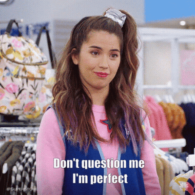 A Woman In A Pink Shirt And Blue Vest Says " Don 'T Question Me I 'M Perfect " In A Store . GIF