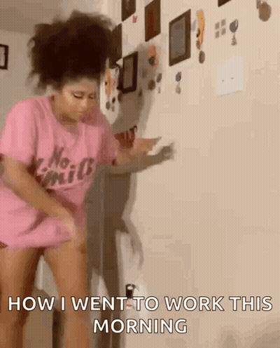 A Woman In A Pink Shirt Is Dancing In Front Of A Wall And Says " How I Went To Work This Morning " GIF