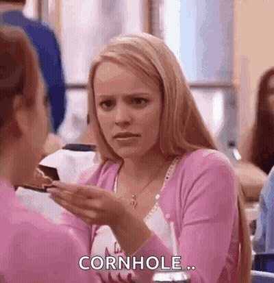 A Woman In A Pink Shirt Is Holding A Piece Of Cake In Her Hand And Talking To Another Woman . GIF