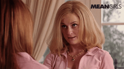 A Woman In A Pink Shirt Is Looking At Another Woman In Front Of A Window With Meangirls Written On The Bottom GIF
