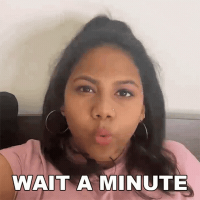 A Woman In A Pink Shirt Is Making A Funny Face And Says Wait A Minute GIF