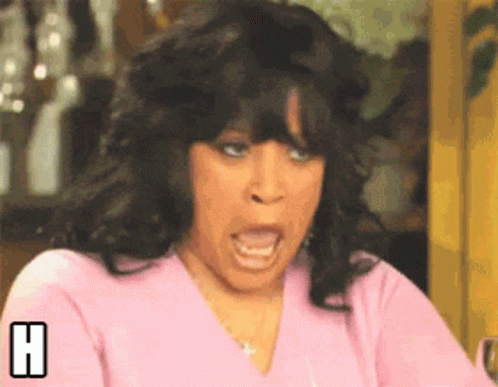 A Woman In A Pink Shirt Is Making A Funny Face With The Letter H Behind Her GIF