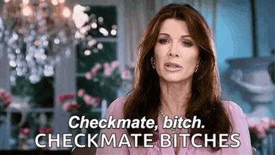 A Woman In A Pink Shirt Is Saying Checkmate Bitch Checkmate Bitches In Front Of A Chandelier . GIF