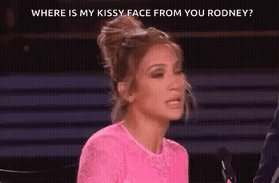 A Woman In A Pink Shirt Is Sitting In Front Of A Microphone . GIF