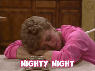 A Woman In A Pink Shirt Is Sleeping At A Table With The Words Nighty Night Written Above Her GIF